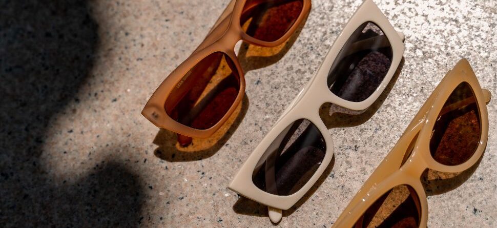 Cuatro pares de gafas de sol fotocromáticas negras alineadas sobre un fondo rosa brillante, destacando su estilo clásico y moderno.