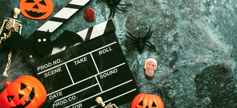 Decoración de Halloween con calabazas, esqueletos y una claqueta de cine. Perfecta para la temática de maratones de películas de terror y noches de Halloween.