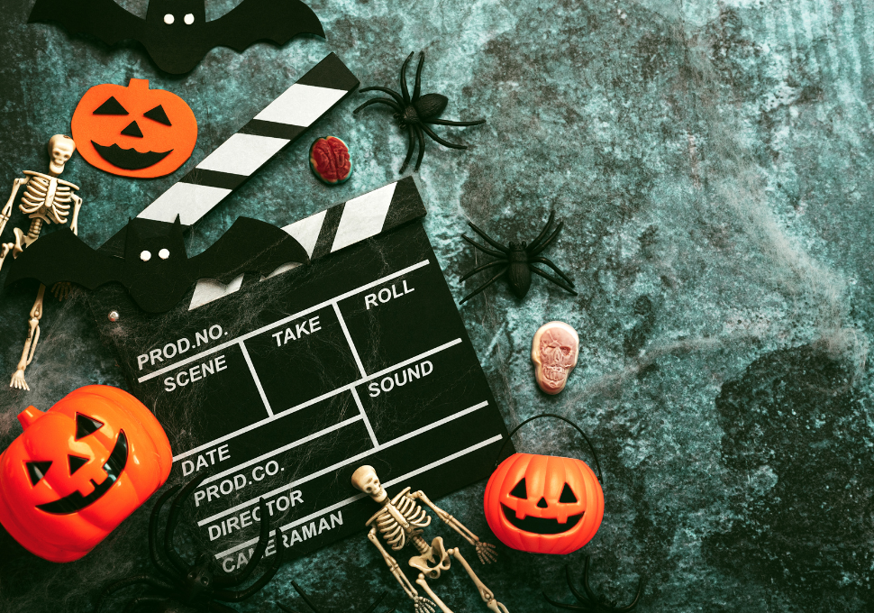 Decoración de Halloween con calabazas, esqueletos y una claqueta de cine. Perfecta para la temática de maratones de películas de terror y noches de Halloween.
