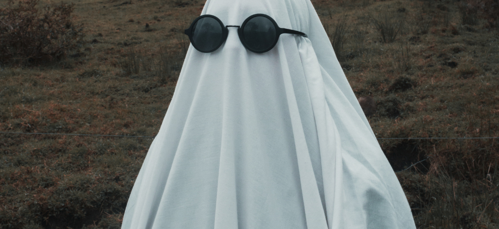 Fantasma con gafas de sol en un entorno rural, combinando humor y estilo en una imagen ideal para celebrar la temporada de Halloween de manera creativa.