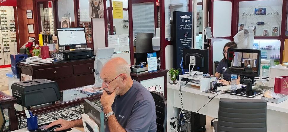 Interior de Óptica Cosmos en Tenerife con personal trabajando en mostradores, ofreciendo atención personalizada en un ambiente acogedor y profesional.