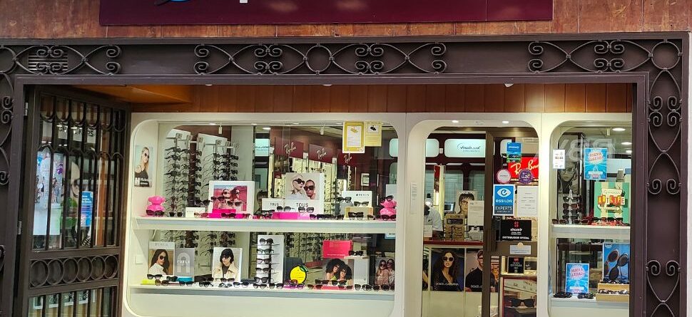 Fachada de Óptica Cosmos en Tenerife, mostrando escaparates con una amplia variedad de gafas de sol y graduadas de marcas reconocidas, reflejando calidad y estilo.