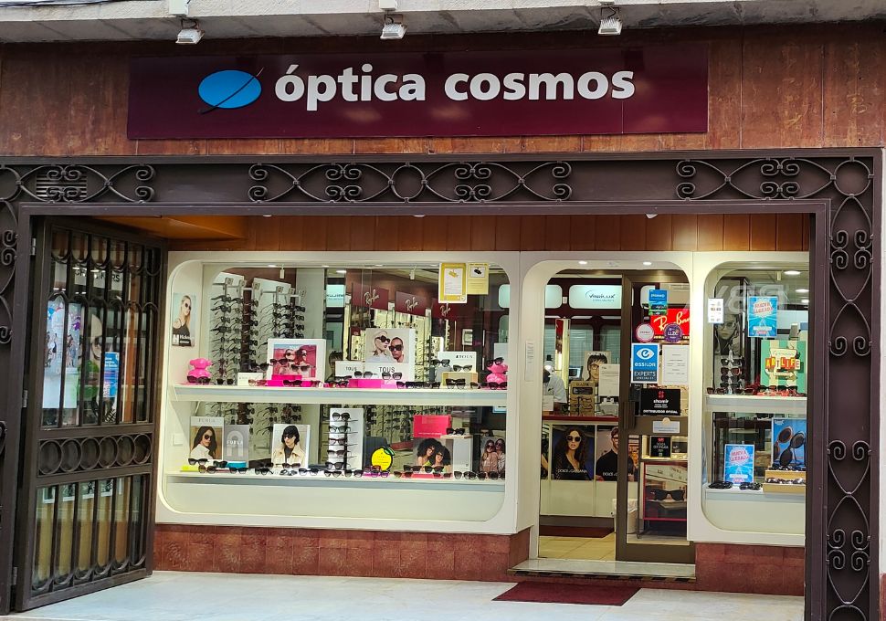 Fachada de Óptica Cosmos en Tenerife, mostrando escaparates con una amplia variedad de gafas de sol y graduadas de marcas reconocidas, reflejando calidad y estilo.