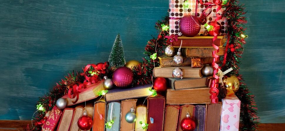 Imagen de libros decorados con adornos navideños: Una pila de libros decorada con luces, bolas y guirnaldas navideñas, creando un ambiente festivo y literario. Perfecto para transmitir el espíritu navideño relacionado con la lectura y los regalos ideales para lectores.