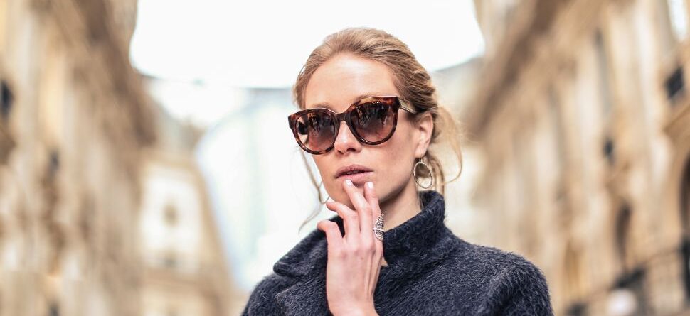 Mujer elegante usando gafas de sol modernas en una calle urbana, destacando estilo y protección ocular en ambientes exteriores.