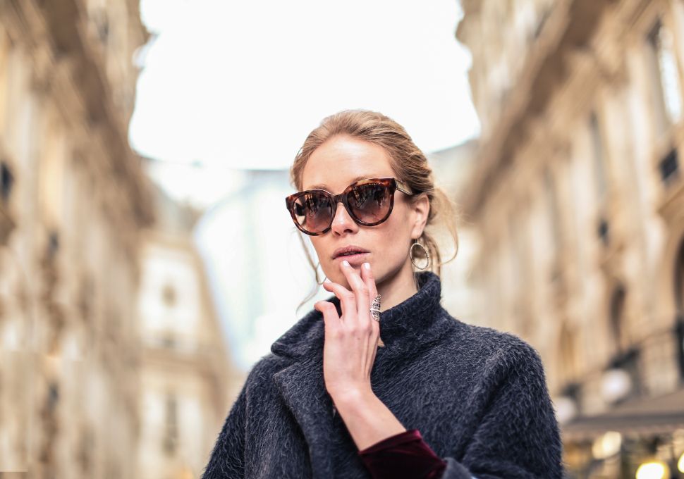 Mujer elegante usando gafas de sol modernas en una calle urbana, destacando estilo y protección ocular en ambientes exteriores.