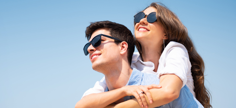 Pareja joven disfrutando del sol con gafas de sol, protegiendo su visión de los rayos UV. Las gafas de sol son esenciales todo el año.
