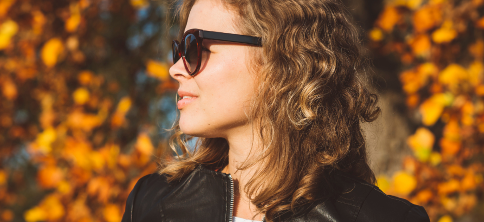 Mujer con gafas de sol en un paisaje otoñal. La radiación solar y la luz reflejada en el entorno hacen que las gafas sean imprescindibles.
