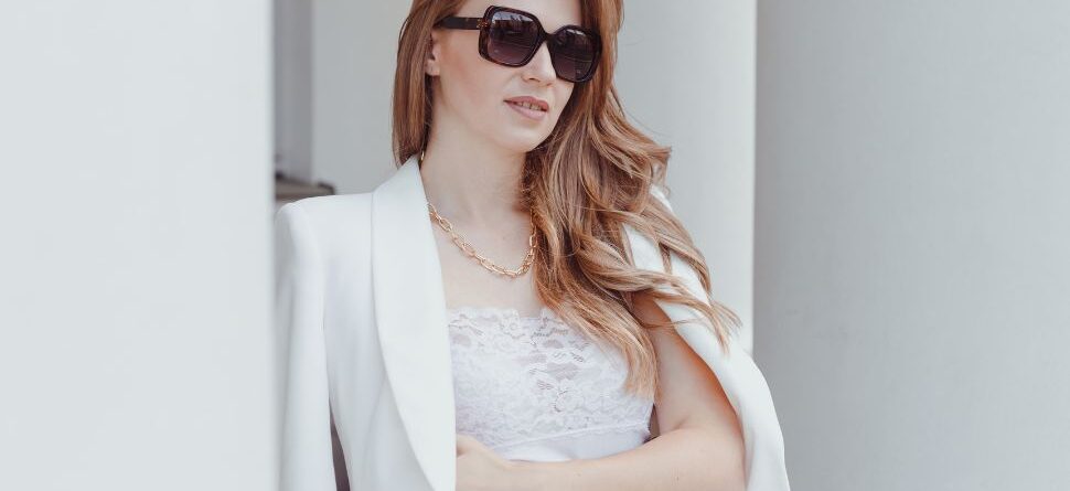 Mujer elegante con gafas de sol polarizadas negras y traje blanco, ideal para proteger la vista en eventos al aire libre durante Semana Santa en Tenerife.