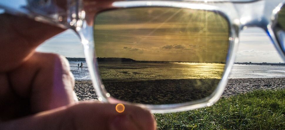 Vista comparativa de una playa soleada a través de unas gafas polarizadas que reducen los reflejos y mejoran la visión, especialmente útil en las costas de Tenerife.