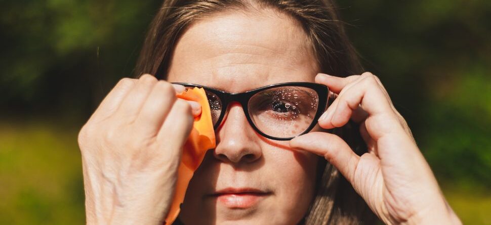 Mujer limpiando cuidadosamente sus gafas con un paño especial para lentes, mostrando cómo mantener una visión clara. Óptica Cosmos Tenerife.
